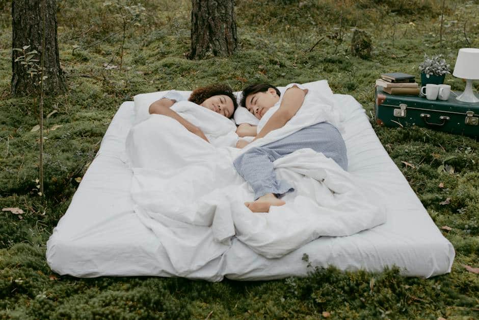 A person sleeping comfortably in a car camping setup, surrounded by nature.